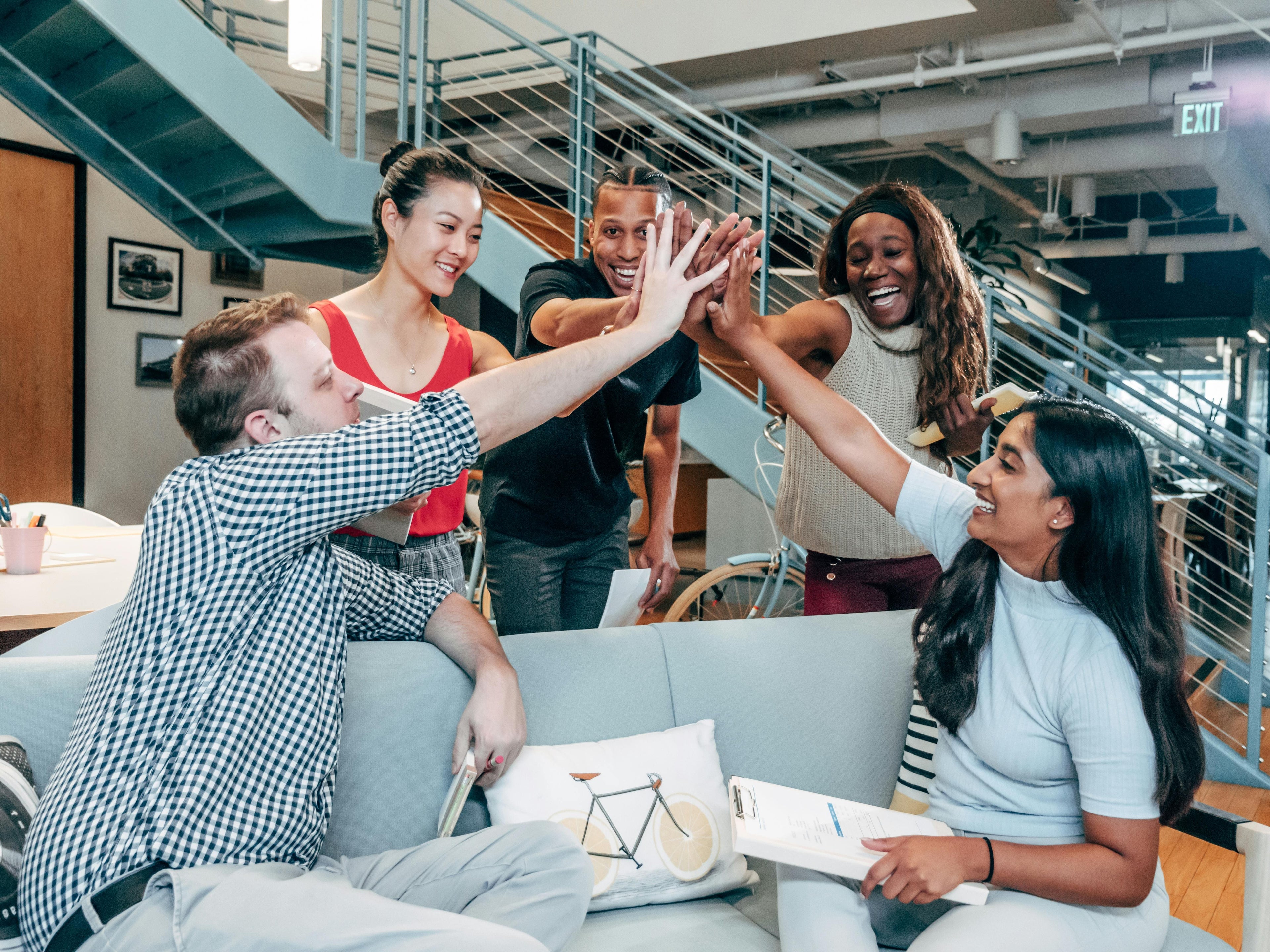Group of people high-fiving in a modern office setting