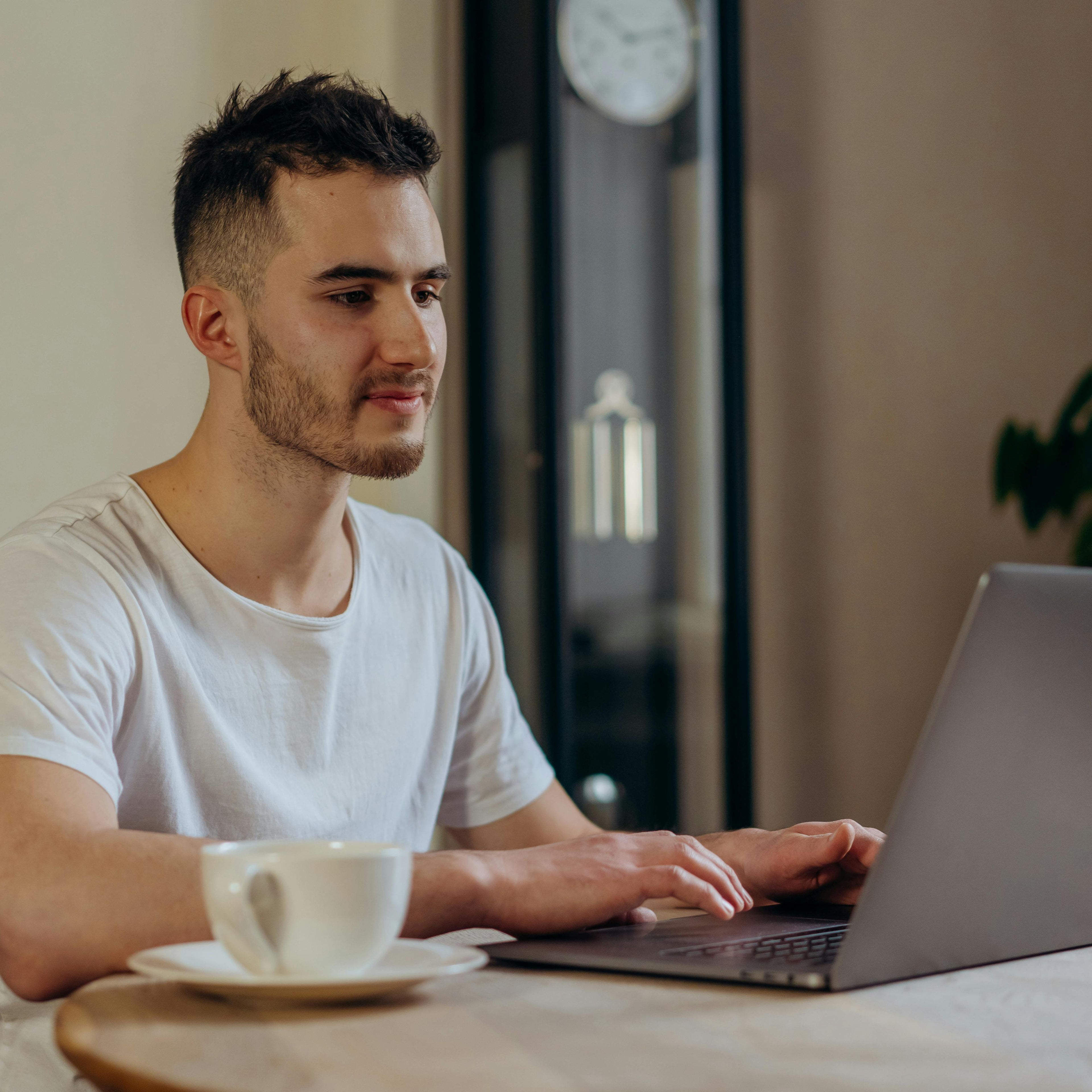 Young man working on laptop with coffee cup, representing focus and productivity benefits of Colossal Health Pure Himalayan Shilajit.